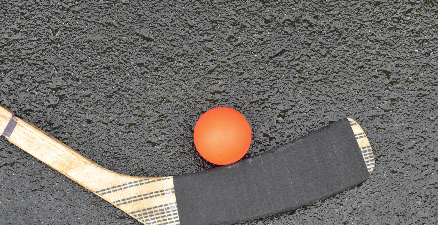 Game Shape — ball hockey stick and ball on wet pavement